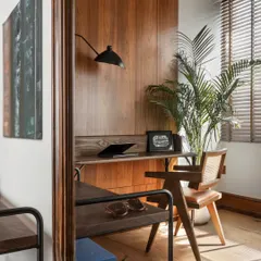 A view into my personal office, showing the warm wood paneling, a sleek wall-mounted lamp, and a caned chair. The space is designed to feel inspiring and professional, a cocoon for creativity and focus.
