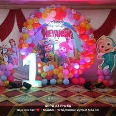 A vibrant and colorful Cocomelon theme for a first birthday party. This setup includes a full balloon arch, character cutouts, and a light-up number '1' to make your child's milestone celebration extra special and fun.