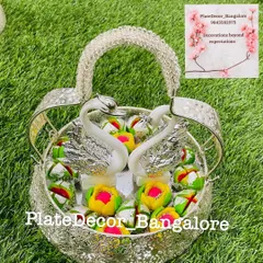 This silver basket with swan figurines holds an assortment of colorful pedas, a popular sweet for festive occasions.