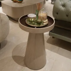 This elegant side table is wrapped in oak veneer with a matte finish, showcasing the beauty of natural wood grain on a curved form. It’s a simple yet sophisticated piece that complements the muted tones of the living room.