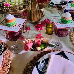 An intimate table setting featuring individual charcuterie boats with cured meats and cheese, alongside custom-branded cupcakes placed elegantly on wine glasses.