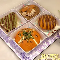 Our 'Party in a Box' for Rakhi offers a global spread of flavors. This assortment includes a creamy kunafa cheesecake slice, a Biscoff cookie, a gooey bombolini, and a savory Korean bun, ensuring there's a treat for every taste.