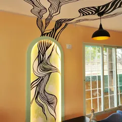 A close-up of the backlit art niche at Essence Cafe. The hand-painted design originates within the arched alcove and extends onto the ceiling, visually connecting different parts of the space.