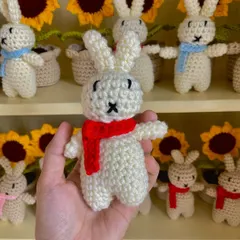 A close-up of a white amigurumi bunny, showing the hand-stitched face details.