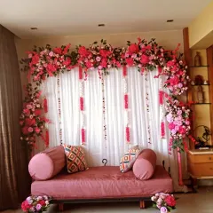 A vibrant engagement or roka decoration done at home. I created a backdrop with a curtain of fairy lights and a full arch of bright pink flowers.