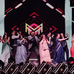 A snapshot of a high-energy group performance on a professionally lit stage with a large LED screen.