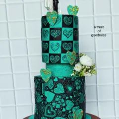 This angle highlights the contrast between the checkered heart pattern and the free-form heart collage on the bottom tier. The addition of 3D hearts with gold detailing adds another layer of texture and sophistication.