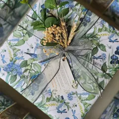 Custom-made gift wrapping paper for these beautiful wedding return favors. The delicate blue and green floral print is complemented by an elegant organza ribbon and a sprig of dried botanicals.