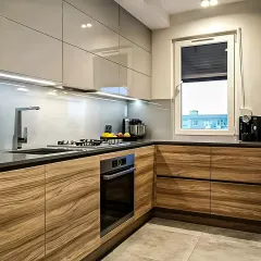 This L-shaped modular kitchen features a dual-tone design with high-gloss grey upper cabinets and warm wood-grain lower units. We've integrated under-cabinet LED lighting for task illumination and built-in appliances for a seamless, modern look.