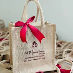 A close-up of a custom-printed jute bag for M.P. Jewellers, adorned with a festive red ribbon. This is a great example of an elegant and eco-friendly branding opportunity for any business.