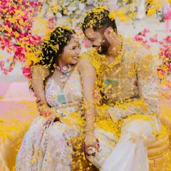 The pure bliss of a Haldi ceremony, as the couple is showered with a cascade of yellow flower petals, their faces lit up with laughter and joy.