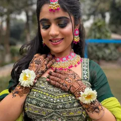 All set for her Mehendi. This close-up shows the beautiful henna, the vibrant jewelry, and the intricately embroidered green blouse.