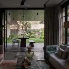 Another view of the living area at Pràna, showing the direct connection to the outdoor dining patio. The large sliding glass doors allow the garden to become a natural extension of the home, perfect for Bangalore's beautiful weather.