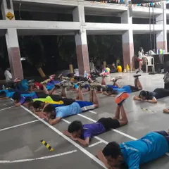 A group of athletes performs a glute-strengthening exercise while lying on the ground. Strong glutes are essential for stabilizing the pelvis and protecting the lower back and hamstrings from strain during intense activity.