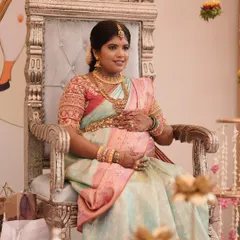 A regal portrait of the mother-to-be, seated on a throne-like chair during her baby shower ceremony. Her embroidered blouse and traditional jewellery complete the look.