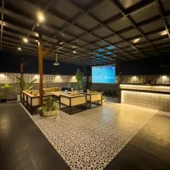 Movie night on the terrace. This wide shot shows a full entertainment setup, including a large projector screen, a long bar counter with mood lighting, and plenty of comfortable seating.