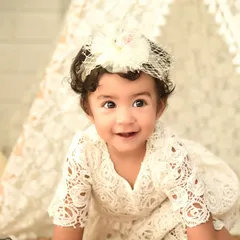 A beautiful close-up from a boho first birthday shoot. Her delicate lace dress and the soft background create a dreamy and innocent portrait.