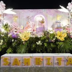For this enchanted forest stage, I used a dense arrangement of flowers and greenery at the base to create the feeling of a real forest floor. The setup is completed with custom name blocks, large paper flowers, and glowing butterfly props.