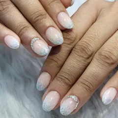 A beautiful and delicate glitter ombre. This design blends a sheer nude base into a soft, iridescent glitter tip, with a rhinestone accent at the cuticle for extra sparkle.