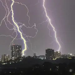 Another perspective of the urban thunderstorm, showing the contrast between the dark silhouettes of the buildings and the bright, chaotic energy of the lightning.