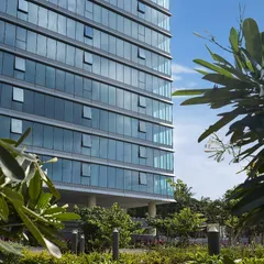 The glass facade of the Godrej Centre Development, featuring operable windows that give users control over their immediate environment. The building is framed by mature trees, demonstrating our commitment to biophilic modern workspace ideas.