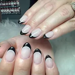 Simple, chic, and always in style. A classic French manicure with glossy black tips on a rounded almond shape.