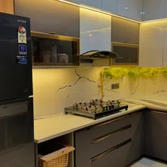The right lighting and details can make a kitchen truly special. Here, the combination of under-cabinet lights, a lit-up glass cabinet, and decorative plants on the backsplash adds a lot of character.