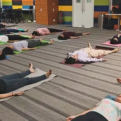 A wide shot of the final relaxation during a corporate yoga class. It's powerful to see a team resting together, taking a collective pause from their busy workday.