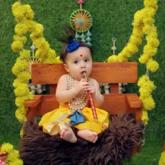 Capturing the playful innocence of a baby dressed as Krishna, sitting on a decorated swing. We focus on creating a comfortable and engaging environment for the most natural expressions.