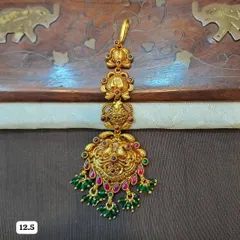 A beautiful 92.5 silver, gold-plated maang tikka featuring a traditional peacock design. The piece is embellished with red and green stones and green bead drops, perfect for a festive look.