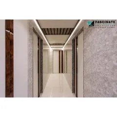 This image showcases a long passageway in a Bhiwandi residence. We used continuous linear lighting on the ceiling and textured wall panels to create a visually interesting and well-lit path through the home.