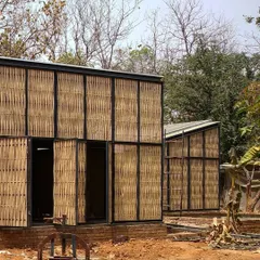 A work-in-progress view of the bamboo screen facade at the Artist Residency. This shot shows the modular nature of the design, with individual steel-framed panels being clad in hand-woven bamboo, creating a textured and breathable building skin.