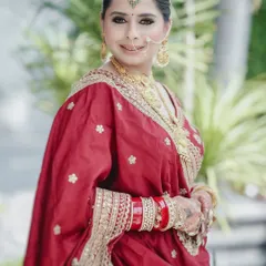 A classic bridal portrait showcasing the bride's beautiful red and gold sari, traditional jewelry, and serene smile.