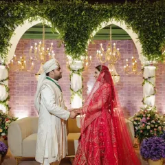 The couple, Arushi and Anirudh, share a moment during their Greek themed wedding ceremony. The backdrop features classic arches draped in greenery, creating a timeless and romantic setting for their vows.