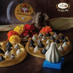 Our Ganesh Chaturthi special box of modaks, featuring a mix of dark, white, and marbled chocolate pieces. A large white chocolate modak mold sits in the foreground, showing the traditional shape we honor.