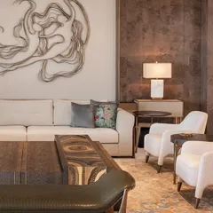 A closer look at the interplay of textures and art. The neutral-toned sofa and plush chairs provide a calm foundation for the expressive metal wall sculpture, creating a focal point that is both dynamic and elegant.