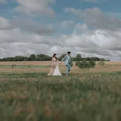 A romantic walk through a field under a dramatic sky. This shot from a UK wedding captures the feeling of a classic love story, blending nature with romance.