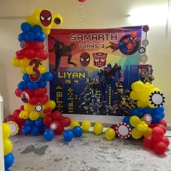 For a joint birthday party, I combined the Spiderman and Transformers themes. This setup features a custom banner for both kids and balloon columns in the classic red, blue, and yellow superhero colors.
