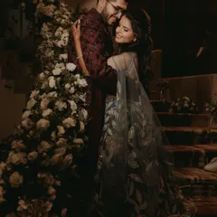 A romantic embrace between the couple on their Sangeet night, surrounded by elegant floral decorations.