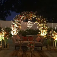 A full view of the rustic-chic reception stage, showcasing the beautiful floral arch, comfortable seating for the couple, and ambient lighting that creates a warm and inviting focal point for the evening.