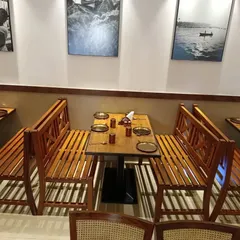 This seating arrangement features custom-made solid wood benches with a classic 'X' back design. This type of sturdy, slatted construction is ideal for high-traffic restaurant environments.