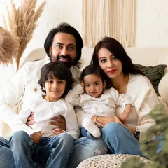 A classic posed family portrait of a family of four on a comfortable couch in my studio. This setup allows for both formal and relaxed group photos.