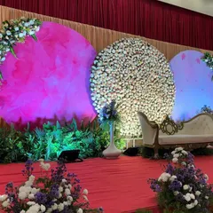 A contemporary stage design with three large circular backdrops. One is covered in pink fluff, another in white flowers, and the third in a soft blue light, creating a multi-textured and visually interesting setting.