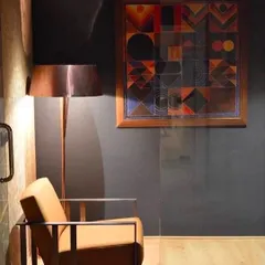 In this private cabin, a dark grey wall and glass partition create a sense of focus. The clean lines of the furniture are softened by a copper floor lamp, adding a spark of vitality and warmth to the minimalist design.