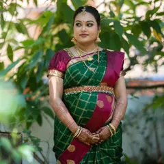 The beautiful Kruthika at her baby shower. Her makeup is soft and traditional, enhancing her natural glow and complementing her green and maroon silk saree.