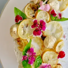 A close-up of the zesty, herby, and unique Lemon Basil cake. I top it with candied lemons, fresh basil leaves, and edible flowers for a dessert that is as beautiful as it is adventurous.