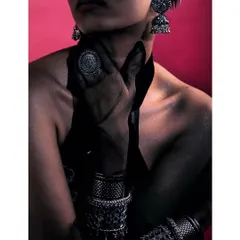 A dramatic shot for a silver jewelry campaign, inspired by Mumbai's fashion scene. The close-up focuses on the intricate details of the stacked bracelets, ring, and earrings against a bold pink background.