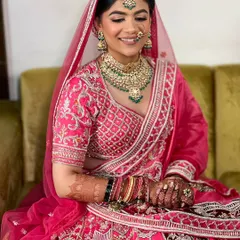 This bride's smile lights up the room. Her hair is styled in a classic bun, allowing her beautiful jewelry and outfit to shine.