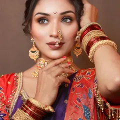A powerful and elegant pose from a traditional bridal shoot. The makeup features sharp, defined eyes and a matte lip, creating a look that is both modern and rooted in tradition.