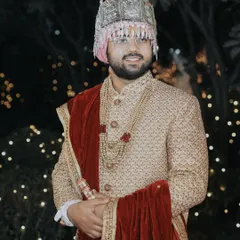 A classic portrait of the groom in his wedding attire. The soft, out-of-focus lights in the background create a beautiful bokeh effect, making him stand out.